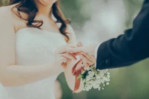 Photographie de mariage Fine Art : plan rapproché intime de la mariée passant l'alliance au doigt du marié, par photographe de mariage professionnel à Digne-les-Bains. Capture de l'engagement.