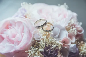 Alliances argentées posées sur un bouquet de mariée aux tons pastel.