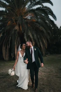 Photographe mariage Forcalquier 04 - Mariés souriants qui marchent devant un palmier Alpes-de-Haute-Provence PACA