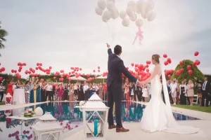 Mariés lâchant des ballons au bord d'une piscine lors d'une réception à Nice.