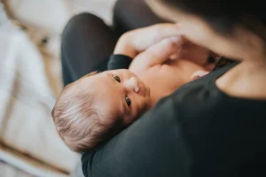un bébé regarde intensément les yeux de sa maman - bébé est en couche dans les bras de sa maman