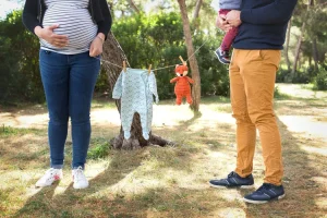 une famille qui a accroché un body de bébé et un petit doudou sur une corde a linge pour annoncer l'arrivée prochaine d'un heureux évènement - photographe pro famille oraison
