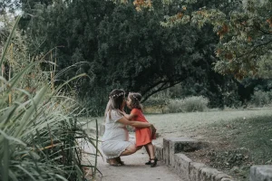 une maman et sa jeune fille qui s'embrasse dans un parc à l'heure bleue