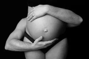 papa enlace le ventre enceinte de la maman avec ses deux bras en noir et blanc - photo studio à domicile