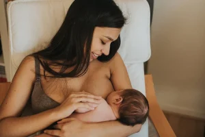 femme qui allaite son enfant assis sur une chaise de repos en carressant le bras de son enfant
