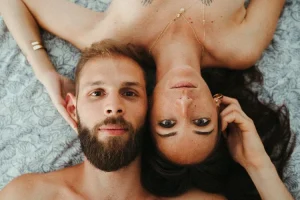 un couple allongé sur un lit avec la tete posé l'un contre l'autre se prenant chacun la tete de l'autre dans la main