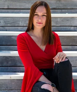 Regard fixe et insistant d'une femme en haut rouge assise sur les marches d'un escalier