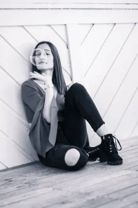 jeune femme qui joue avec une bulle de savon - assisse sur une terrasse en bois