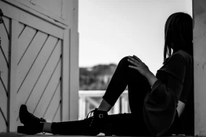 femme qui pose la main sur sa jambe regardant le paysage assis sur une terrasse