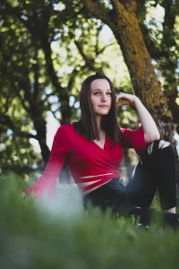 Jeune femme souriante assis sur un parterre d'herbe dans un coin fleuri des alpes de haute provence