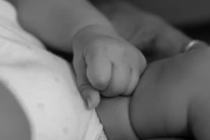 bébé qui ferme le point fort posé sur sa jambe en noir et blanc