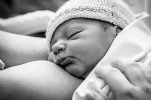Un bébé s'endort sur la poitrine de sa maman après avoir pris son repas