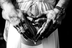 couple qui forme un coeur avec leur main posé sur le ventre de la maman enceinte
