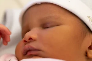 bébé qui s'endort la main levé apres avoir pris son biberon dans les bras lové de papa