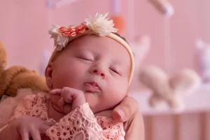 Petite fille qui s'endort dans sa chambre pendant une séance photo de naissance sur un theme rose bonbon