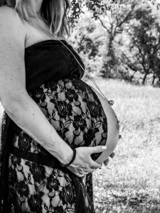 Ventre bien rond d'une future maman qui se tient le bas du ventre