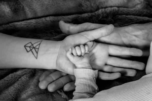 Main de bébé dans la main de maman dans la main de papa à la maternité de Digne-les-bains