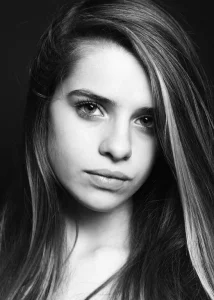 Portrait fin et serré d'une très jeune femme en noir profond qui regarde l'objectif du photographe avec insistance profonde