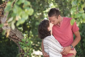 Couple qui s'embrasse devant leur arbre préféré dans un champs de vigne